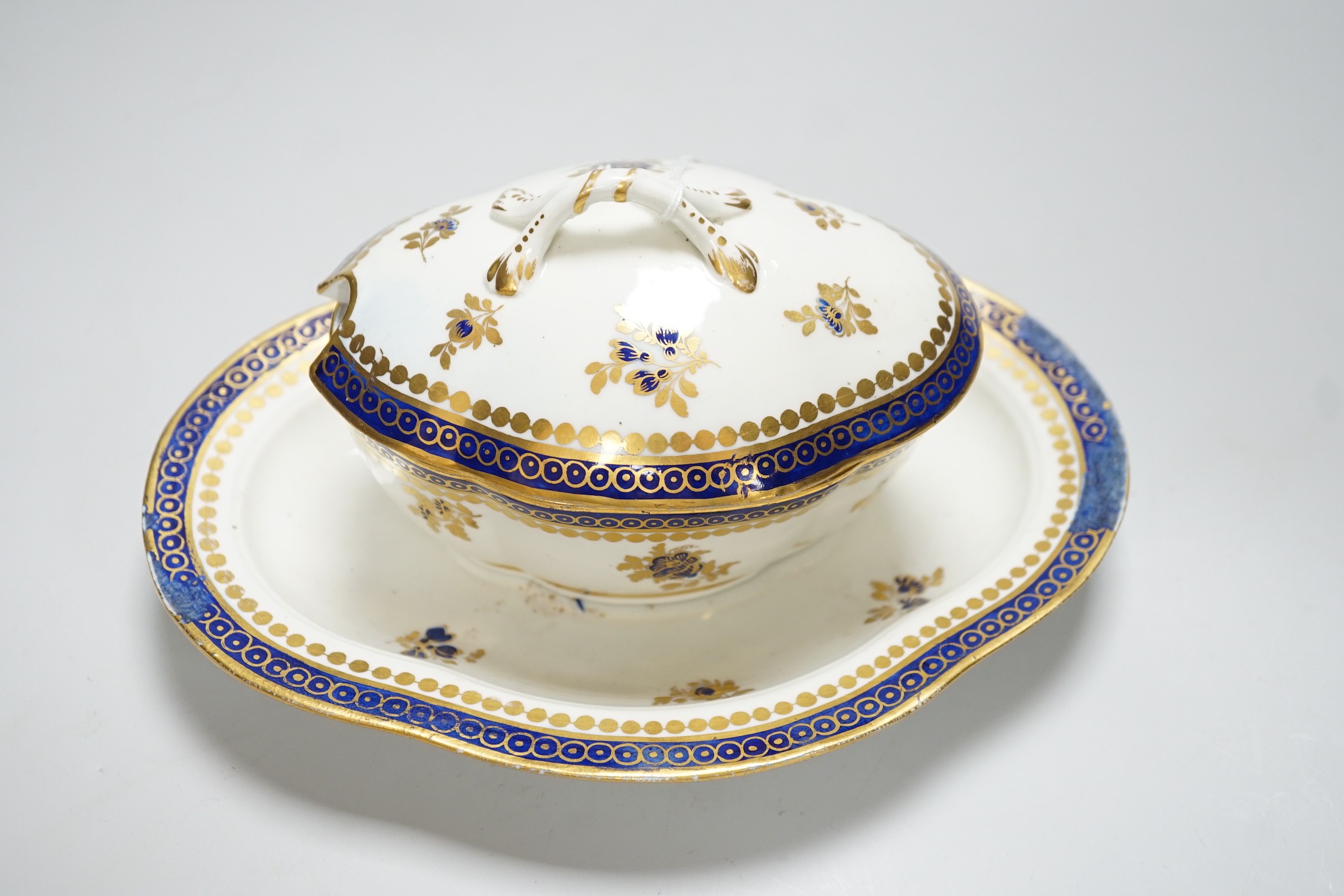 An 18th century Caughley tureen cover and stand with blue and gilt decoration, stand mis-fired to border, S mark to stand and base, stand 23cms wide